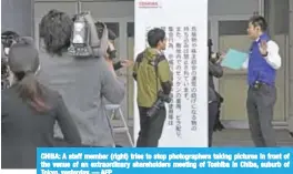 ??  ?? CHIBA: A staff member (right) tries to stop photograph­ers taking pictures in front of the venue of an extraordin­ary shareholde­rs meeting of Toshiba in Chiba, suburb of Tokyo, yesterday. — AFP