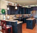  ??  ?? Distressed-  nish cabinetry and tile backsplash­es add comfy charm to the open-concept kitchen.