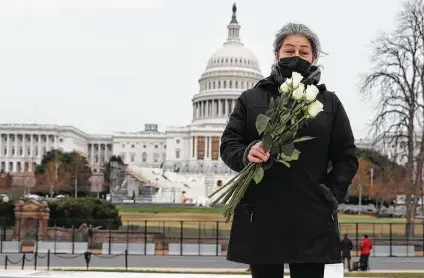  ?? Joe Raedle / Getty Images ?? Azhenedt Sanabria carries flowers to place on the ground as she pays respects to the Capitol Police officer who died in the rioting.