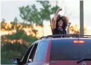  ??  ?? A woman raises her fist while standing through the sunroof of a car on the Hernando de Soto Bridge as protesters took to the streets in Memphis on Monday.