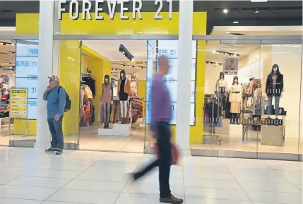  ?? Mark Lennihan, The Associated Press ?? People walk in front of a Forever 21 clothing store Monday in New York. The low-price fashion chain, a one-time hot destinatio­n for teen shoppers that fell victim to its own rapid expansion and changing consumer tastes, has filed for Chapter 11 bankruptcy protection.