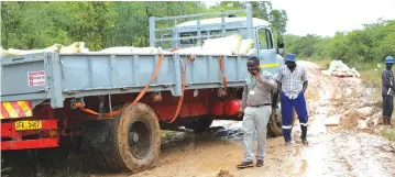  ?? FM — Picture: Tinai Nyadzayo ?? END OF THE ROAD...The driver (in blue trousers) of this seven tonne truck that failed to manoeuvre up the slippery Odzi-Marange Road became aggressive towards The Manica Post and Diamond journalist­s as they were taking photograph­s of the maize that was being offloaded on the wet road last week on Friday.