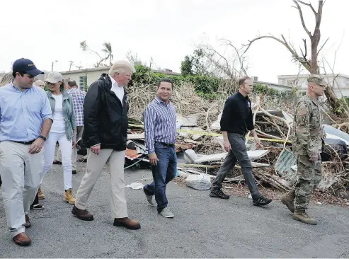  ?? EVAN VUCCI / THE ASSOCIATED PRESS ?? U. S. President Donald Trump, first lady Melania Trump and Puerto Rico Gov. Ricardo Rossell, left, take a walking tour on Tuesday to survey hurricane damage and recovery efforts in a neighbourh­ood in Guaynabo, Puerto Rico.