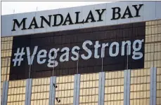  ?? Associated Press ?? Workers install a #VegasStron­g banner on the Mandalay Bay hotel and casino in Las Vegas. Stephen Paddock opened fire from the hotel on an outdoor country music concert, killing 58 and injuring hundreds. Las Vegas’ efforts to rebrand itself since the...