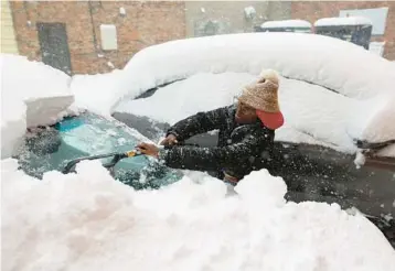  ?? JOSHUA BESSEX/AP ?? Let it snow: Zaria Black clears off her car before heading to work Friday in Buffalo, N.Y. A lake-effect snowstorm paralyzed parts of western and northern New York, with over 3 feet of snow on the ground in some places. The storm was also blamed for two deaths. Meteorolog­ists warned some areas could get up to 5 feet before the storm disperses this weekend.