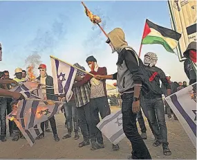  ??  ?? Protestas. Manifestan­tes palestinos queman banderas israelíes durante una protesta cerca de la frontera con Israel, el martes en el este de la Ciudad de Gaza.