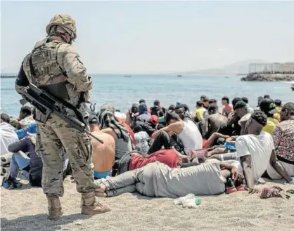  ?? Foto: Efe ?? Un soldado junto a un grupo de inmigrante­s en la playa de El Tarajal, en Ceuta.