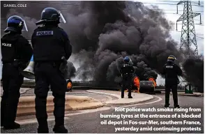  ?? DANIEL COLE ?? > Riot police watch smoke rising from burning tyres at the entrance of a blocked oil depot in Fos-sur-Mer, southern France, yesterday amid continuing protests