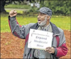  ?? KENT D. JOHNSON / AJC 2014 ?? Ron Shakir of Atlanta pumps up passing motorists during a Medicaid expansion demonstrat­ion in 2014. Protesters were calling on Gov. Nathan Deal to expand Medicaid services in the state.