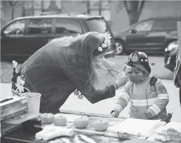  ?? TAYLOR GLASCOCK/THE NEW YORK TIMES ?? A child’s temperatur­e is checked before entering a “Trunk-or-Treat” Halloween event in Chicago on Saturday.