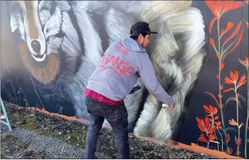  ?? PHOTOS BY RICK SILVA — PARADISE POST ?? Christian Garcia helping paint a wolf on the building. Garcia said that Shane Grammer, who he met a couple of years ago, was already working on the mural but knew that Grammer was in need of a wall.