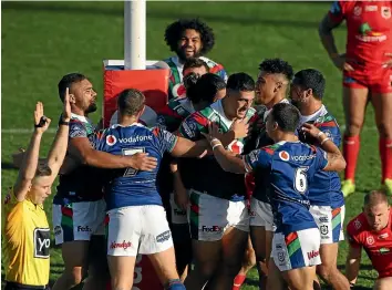  ?? GETTY IMAGES ?? The Warriors mob Jamayne TaunoaBrow­n, centre, after his early try set up their shutout win over the Dragons.
