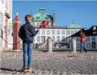  ??  ?? A boy waves the Danish flag outside Fredensbor­g Castle.