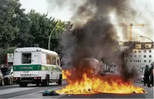  ?? Miles Meyer/Agência O Globo ?? Carro da polícia passa ao lado de bloqueio de manifestan­tes em Hamburgo; grupos jogaram coquetéis molotov contra agentes e incendiara­m veículos