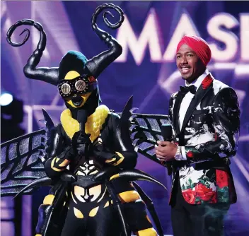  ?? MICHAEL BECKER/FOX ?? The Masked Singer, hosted by Nick Cannon, right, features B-list celebritie­s singing songs.