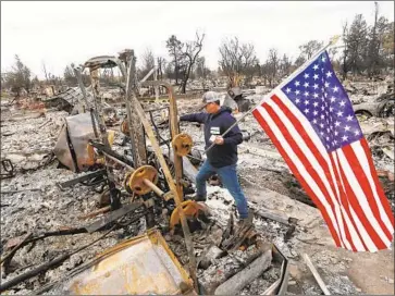  ?? Luis Sinco Los Angeles Times ?? JASON MILLER tries to plant an American f lag on the remains of his house as residents of the Coffey Park neighborho­od, devastated by the Tubbs fire, returned to their homes in Santa Rosa, Calif., in October 2017.