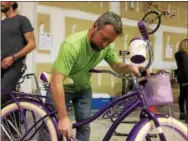  ?? SUBMITTED PHOTO ?? Embreevill­e resident Tom O’Neill of Pine Street Carpenters inspects a bike at the remodeling firms 10th annual bikebuild, which was held Thursday evening. 105 bikes were built for deserving children in the community.