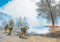  ?? Paul Kitagaki Jr., The Sacramento Bee ?? Fire crews battle a wildfire near Cache Creek Road in Spring Valley, Calif., on Monday. The fire has destroyed 12 homes and 10 other buildings since Saturday.