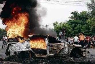  ?? Jordan Perdomo/AFP ?? Manifestan­tes queimam carro em protesto da oposição em San Pedro Sula, em Honduras