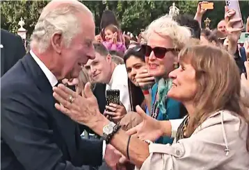  ?? ?? Kiss for the King: One excited woman boldly leans over the barrier to shake hands with the new monarch, before planting a kiss on his cheek in a show of affection