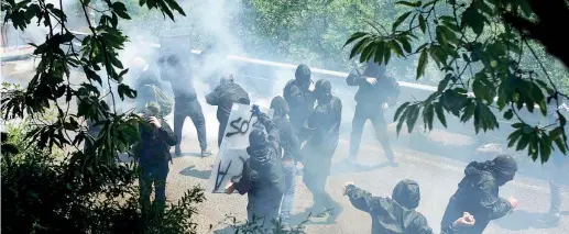  ??  ?? Sotto tiro Black bloc e militanti dei centri sociali tentano di mettersi al riparo dai lacrimogen­i e dagli idranti delle forze dell’ordine dopo l’assalto al cantiere in Val di Susa