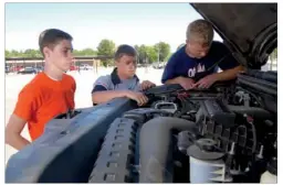  ?? RUSTY HUBBARD/RIVER VALLEY & OZARK EDITION ?? Layne Woods, from left, Scott Roland and Ty Hunt take a peek under the hood of a Ford F150 pickup.the students worked to plan the 2012 Fourche River Days Car & Truck Show.