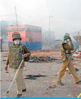  ?? — AFP ?? NEW DELHI: Policemen stand on a vandalized road following clashes between supporters and opponents of a new citizenshi­p law, at Bhajanpura area of New Delhi yesterday.