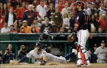  ?? The Associated Press ?? SLIDING IN: Houston Astros’ Carlos Correa scores past Washington Nationals catcher Kurt Suzuki on a single by Josh Reddick Friday during the second inning of Game 3 of the World Series in Washington. The Astros defeated the Nationals, 4-1.