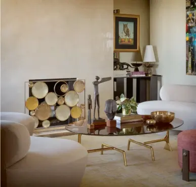  ??  ?? From left: The curved forms of the console, mirror and decorative pieces reflect the architectu­ral elements of this alcove; The moonstone-andgold firescreen is an ornamental highlight in the living room Opposite page: Metallic details on the armchairs and coffee table bring an extra layer of shine to the living area; The chevron tiles create visual interest in the minimalist bathroom; Vertical fumed wood panels throughout the kitchen and living area add warmth to the space