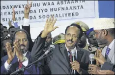  ?? AP ?? New Somali President Mohamed Abdullahi Farmajo (center) waves to supporters as he is joined by incumbent President Hassan Sheikh Mohamud (left) after winning the election in Mogadishu on Wednesday.