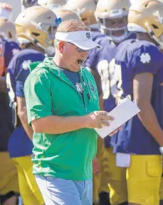  ?? AP ?? Coach Brian Kelly looks at notes during practice last week. Will Notre Dame battle for a College Football Playoff spot this year?