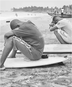  ??  ?? Surfers concentrat­e on their board before competing in the internatio­nal surf day competitio­n in Ghana.