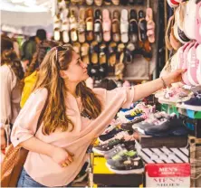  ?? AFP ?? A woman inspects a shoe at the main market of the Kurdish-majority city of Qamishli in Syria’s northeaste­rn Hasakeh province, ahead of the upcoming of Eid Al-Fitr.