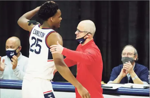  ?? David Butler II / Associated Press ?? UConn coach Dan Hurley, right, hugs senior forward Josh Carlton on the sideline in the final seconds of play against Georgetown on Saturday.