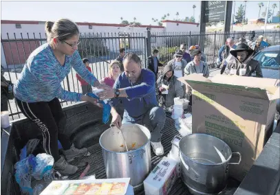  ?? Richard Brian ?? Las Vegas Review-journal @vegasphoto­graph Homeless advocates Elizabeth Hernandez and Matthew Romero hand out warm meals Nov. 22 on Foremaster Lane.