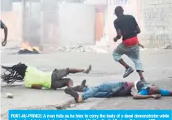 ??  ?? PORT-AU-PRINCE: A man falls as he tries to carry the body of a dead demonstrat­or while police shoot during clashes in the center of Haitian Capital Port-au-Prince. — AFP