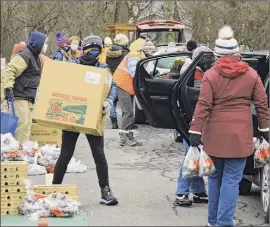  ?? Paul Buckowski / Times Union ?? Volunteers load food bags and boxes into vehicles during a mass food distributi­on put on by Catholic Charities of the Diocese of Albany, and the Regional Food Bank of Northeaste­rn New York at Macedonia Baptist Church last January in Albany.