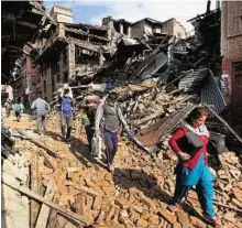  ?? AP ?? Recovering belongings Residents carry belongings from their destroyed homes as they walk through debris caused by the earthquake in Bhaktapur on the outskirts of Kathmandu.