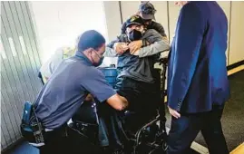  ?? SCOTT MCINTYRE/THE NEW YORK TIMES PHOTOS ?? Brown is helped into the aisle chair. For passengers who use wheelchair­s, air travel can be embarrassi­ng, uncomforta­ble and perilous.