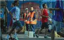  ?? Alexander Zemlianich­enko / Associated Press ?? Two municipal workers stand ready to clean an area ahead of a World Cup match at Moscow’s Luzhniki Stadium.