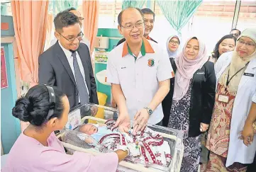  ??  ?? Madius (centre) shows the safety device attached on Rosyati Bayet and her child at the event. — Bernama photo