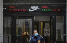  ?? (AP/Bebeto Matthews) ?? A security guard leaves the New York Stock Exchange building Tuesday as a ticker above the doorway carries the latest trading informatio­n. Stocks had a mixed day on Wall Street, but the S&P 500 closed with another record high.