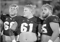  ?? PHELAN M. EBENHACK/AP ?? UCF offensive linemen Josh McMullen, from left, Parker Boudreaux and Cole Schneider watch from the sideline during a win over Connecticu­t last season.