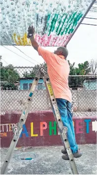  ?? CONTRIBUTE­D PHOTOS ?? Spray paint is applied to the plastic bottles as a final touch in the creation of the canopy.