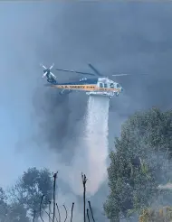  ?? FREDERIC J. BROWN / AFP / GETTY IMAGES ?? A helicopter drops water over a house on a hilltop on Wednesday in Bel Air, as wind-whipped wildfires raged across the Los Angeles region.