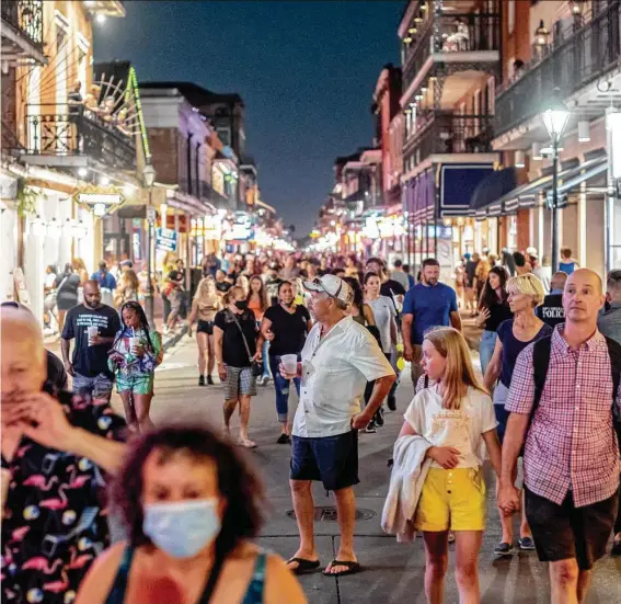  ?? Emily Kask / For the Washington Post ?? These visitors in July to New Orleans’ Bourbon Street now would have to show proof of at least one COVID vaccine dose or a negative PCR test to dine or drink inside.