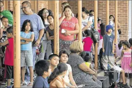  ??  ?? Familieswa­it at Allan Elementary on Monday to get free school supplies. The annual event has grown, forcing Manos de Cristo to limit the number of children it can serve to about 2,000.“I knowthat there are a lot of people that need help,”volunteerP­atrick Pulido said.