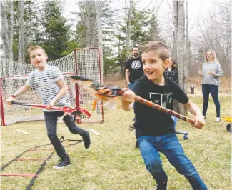  ??  ?? Malik and Liam Frenette play lacrosse with their bubble family as their parents cheer them on.