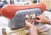  ?? MARLA BROSE/JOURNAL ?? Miniature artist Tim Prythero places a tiny container of mustard atop a counter on “Hot Dog Stand.”