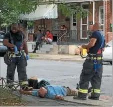  ?? L.A. PARKER — THE TRENTONIAN ?? Firefighte­rs wait for paramedics to tend to a man passed out on the sidewalk, apparently intoxicate­d.